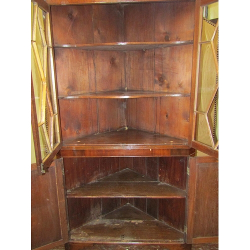 1596 - A Georgian oak freestanding corner cupboard, the lower section enclosed by a pair of panelled doors,... 