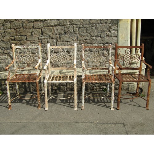 1075 - A set of four old iron strapwork garden chairs, with entwined and scrolled backs and lattice seats o... 