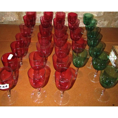 144 - Twenty five cranberry red baluster wine glasses on slender stems, and eight green baluster wine glas... 