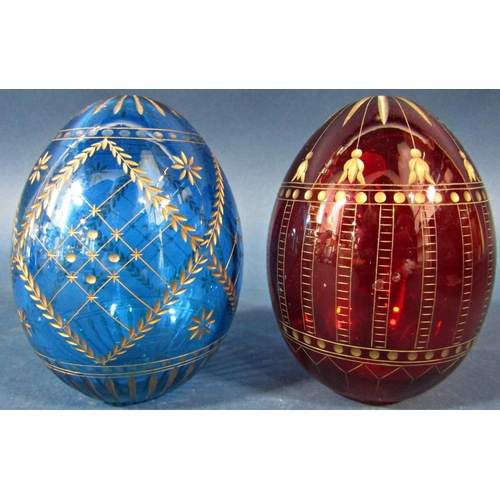 151 - A red cut glass Faberge style Easter egg with a repeating gilded design and another blue egg with gi... 