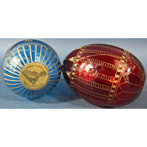 151 - A red cut glass Faberge style Easter egg with a repeating gilded design and another blue egg with gi... 