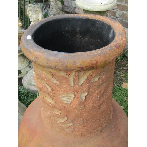 1026 - A weathered clay chimenea with sunburst mask detail, and raised on a simple iron work stand, 98 cm h... 