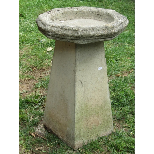 1050 - A weathered cast composition stone bird bath of octagonal form with script, 40 cm diameter raised on... 