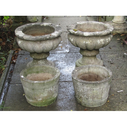 1006 - A pair of weathered cast composition stone garden urns, the squat circular bowls raised on loose soc... 