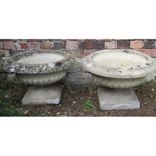 1037 - A pair of weathered cast composition stone garden urns, squat circular bowls with flared egg and dar... 