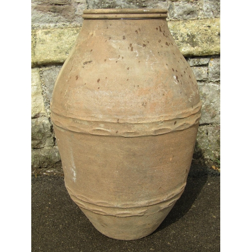 1080 - An old terracotta olive jar oviform with thumb pressed ring bands, 68 cm high