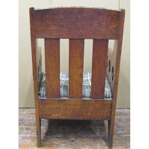 1625 - An arts and crafts elbow chair, with upholstered seats and back panel, the framework with pierced de... 