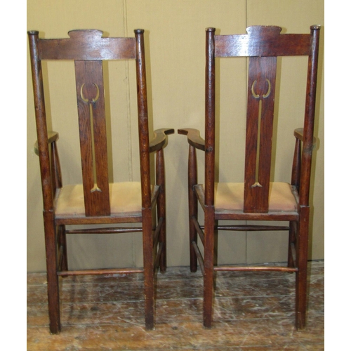 1629 - A pair of arts and crafts elbow chairs in oak with pierced splats, upholstered seats, on turned supp... 