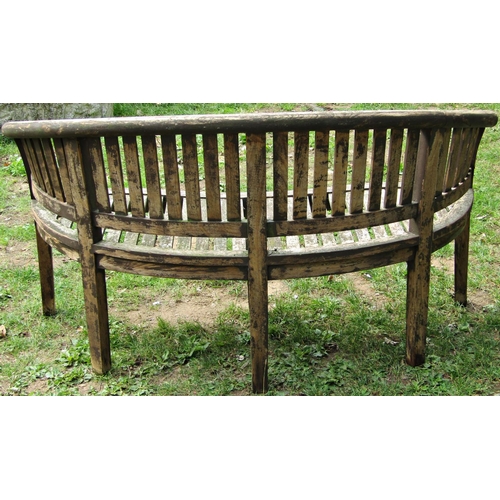 1059 - A stained hardwood banana shaped garden bench 160 cm wide