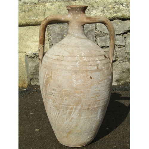 1089 - An old buff coloured terracotta amphora with drawn bottleneck, moulded open loop handles and simple ... 