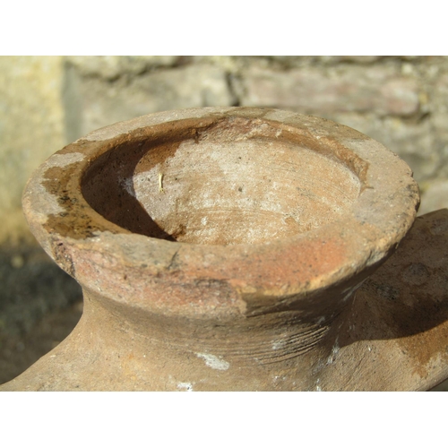 1089 - An old buff coloured terracotta amphora with drawn bottleneck, moulded open loop handles and simple ... 