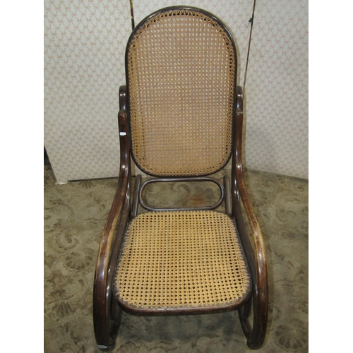 1201 - A vintage Bentwood rocking chair with cane panelled seat and back stamped Thonet, Austria