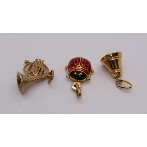 304 - Three 9ct charms comprising an enamelled ladybird, a French horn and a bell, 3.6g total