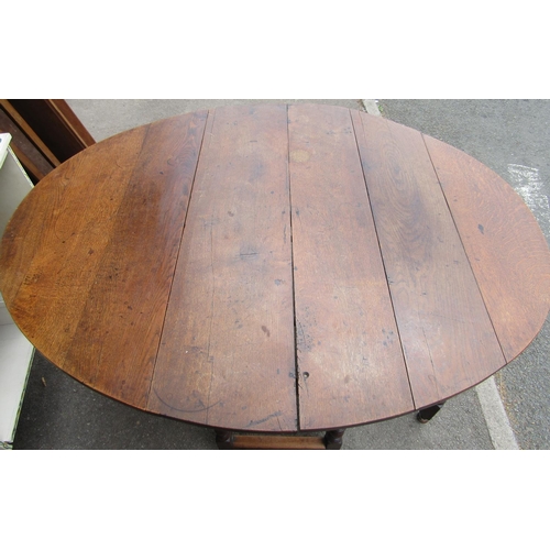 1307 - A Georgian oval drop leaf gateleg dining table, principally in oak, raised on six turned supports un... 