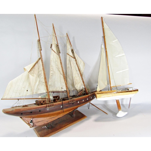 815 - A wooden model of a three masted yacht, 64 cm raised on a wooden stand and a wooden pond yacht.