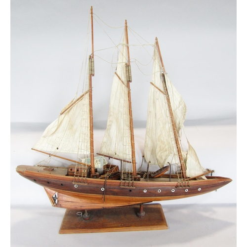 815 - A wooden model of a three masted yacht, 64 cm raised on a wooden stand and a wooden pond yacht.