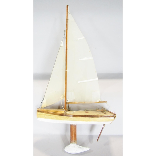 815 - A wooden model of a three masted yacht, 64 cm raised on a wooden stand and a wooden pond yacht.