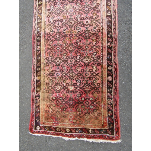 1812 - A Hamadan runner with a repeating geometric pattern on a predominantly pink ground, 500cm x 88cm.