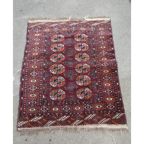 1815 - A Turkoman rug with two rows of elephant foot gul on purple ground, 110cm x90cm