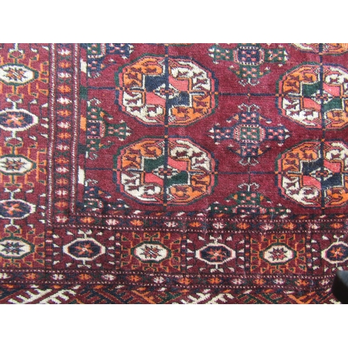 1815 - A Turkoman rug with two rows of elephant foot gul on purple ground, 110cm x90cm