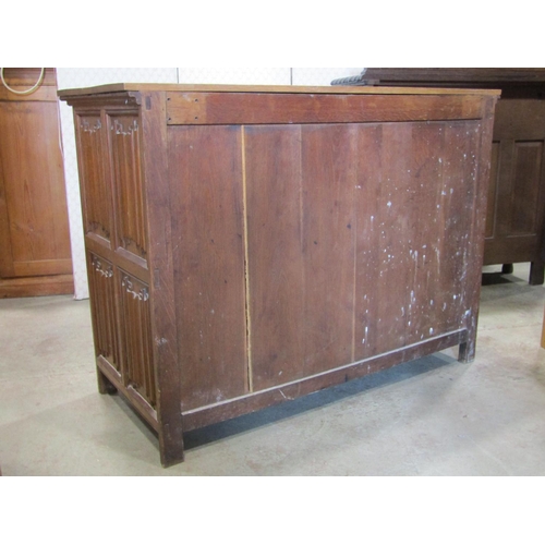 1299 - A Gothic revival oak side cupboard enclosed by a pair of linen fold panelled doors with decorative e... 