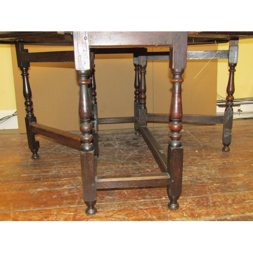 1552 - A Georgian oak gateleg table on turned supports, 130cm long to seat six