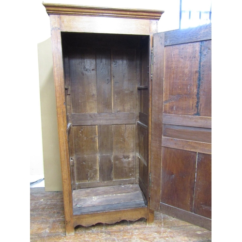 1564 - An early 19th century oak livery cupboard enclosed by a panelled door, within a pegged frame with br... 