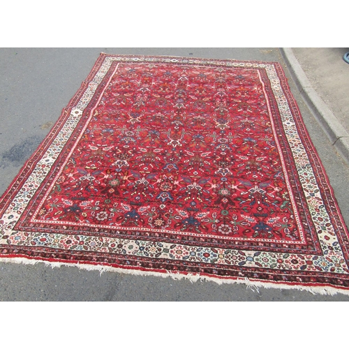 1781 - A large Sarouk design carpet with an all over floral pattern on a red ground, 310cm x 210cm approx