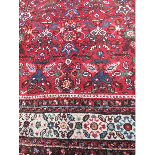 1781 - A large Sarouk design carpet with an all over floral pattern on a red ground, 310cm x 210cm approx