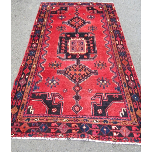 1804 - North east Persian Kurdie rug  with an extended hooked medallion and a geometric border on a red gro... 