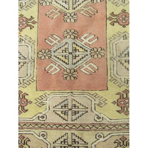 1819 - A Kazak corridor rug with several rows of medallions in faded tones of brown and yellow, 210cm x 120... 