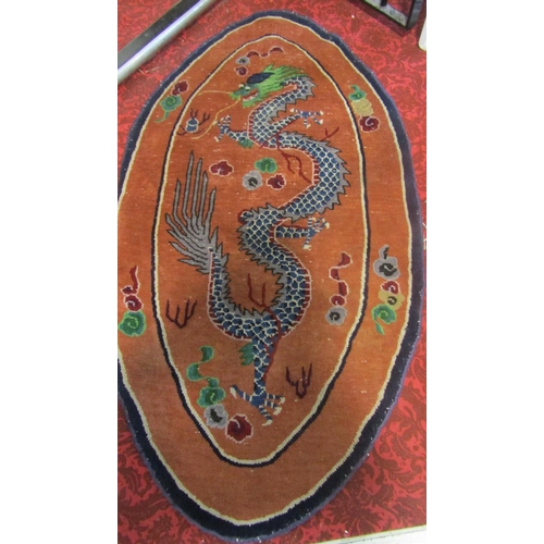 1822 - An oval Tibetan rug with a blue dragon with a green head on an apricot ground 145cm x 78cm approx