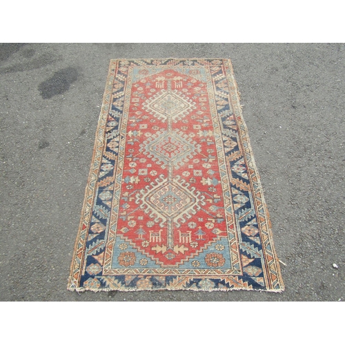 1807 - An old Middle Eastern rug with three interlocking medallions on a red ground, 170cm x 90cm