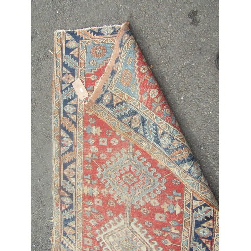 1807 - An old Middle Eastern rug with three interlocking medallions on a red ground, 170cm x 90cm