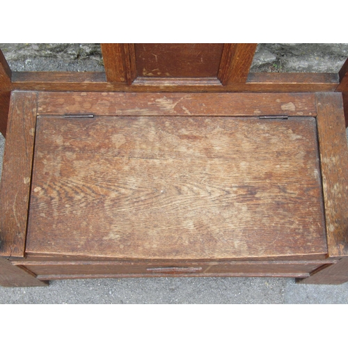 1444 - A 1920s oak hall bench and combined umbrella stand, with hinged box seat, shaped outline and applied... 