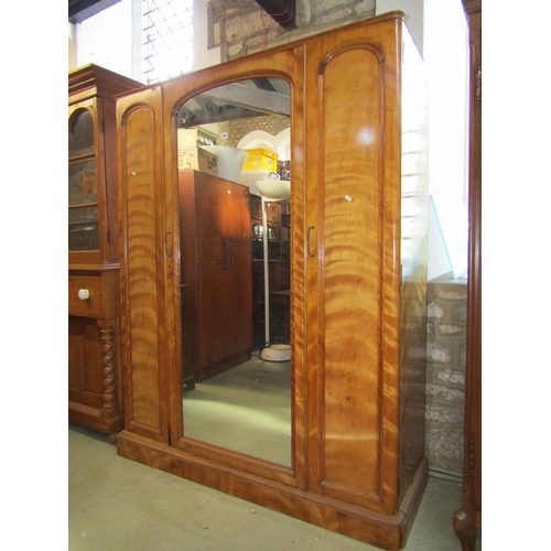 2402 - A Victorian satin birch wardrobe enclosed by three arched panelled doors, the central with mirror pl... 