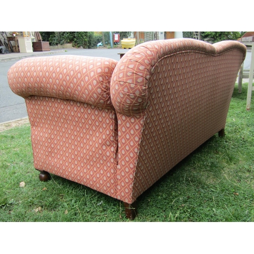 2370 - An Edwardian two seat sofa with rolled arms and single drop end, upholstered in repeating floral lat... 