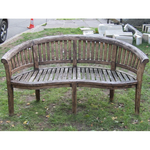 2043 - A stained hardwood banana shaped garden bench 160 cm wide