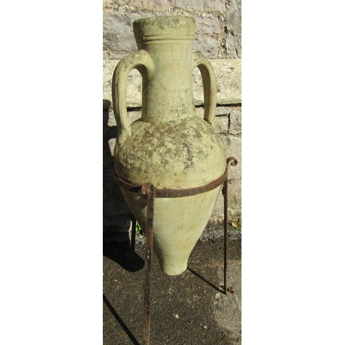 2095 - A small buff coloured weathered terracotta amphora, with moulded loop handles, set within an ironwor... 