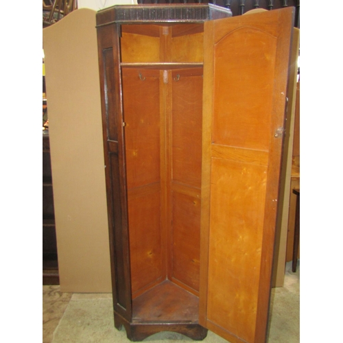 2205 - A 1920s oak floorstanding corner hall/bedroom wardrobe enclosed by a lancet shaped panelled door, 68... 