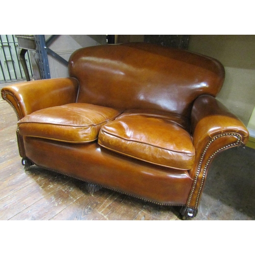 2647 - A traditional two seat leather sofa, with brass stud detail on fluted supports, 145cm wide