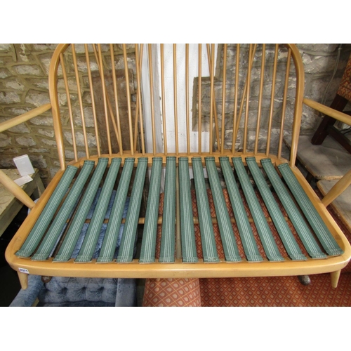 2371 - A vintage Ercol light beechwood Windsor style hoop and stick back two seat sofa, with loose cushions... 