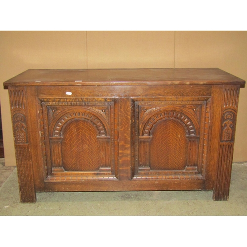 2388 - A reproduction oak coffer with hinged lid, the front elevation with arcaded panels and carved detail... 