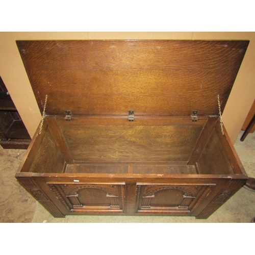 2388 - A reproduction oak coffer with hinged lid, the front elevation with arcaded panels and carved detail... 