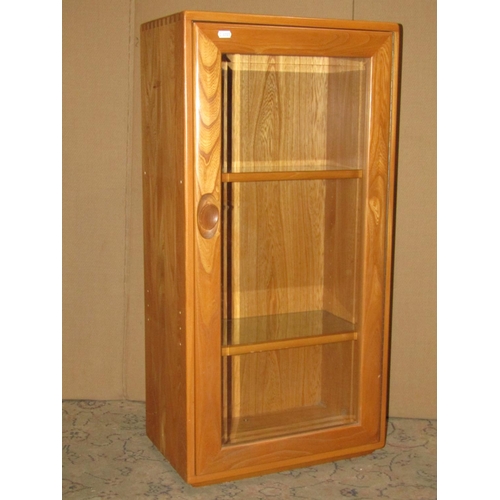 2411 - An Ercol light elm modular side cabinet enclosed by a rectangular bevelled edged glazed panelled doo... 