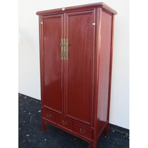 2565 - A red lacquer Chinese wardrobe of tapering form with two panel doors over three drawers, 96cm wide m... 