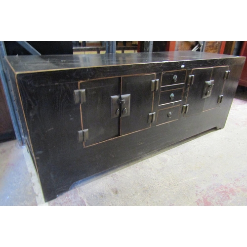 2570 - A Chinese hardwood side board enclosed by an arrangement of doors with central drawers with ebonised... 