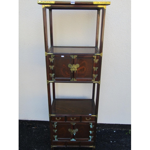 2572 - A Korean open hard wood watnot with overlay brass detail, the upper section with panelled doors and ... 