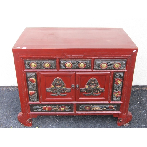 2576 - A Chinese red lacquered cabinet enclosed by cupboards and drawers with carved and painted detail wit... 