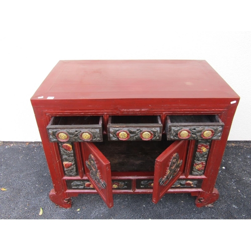 2576 - A Chinese red lacquered cabinet enclosed by cupboards and drawers with carved and painted detail wit... 